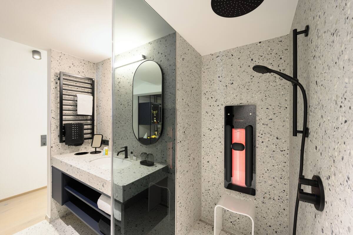 A modern bathroom with a freestanding sink, a large mirror, a towel rack, and a heated towel rail.