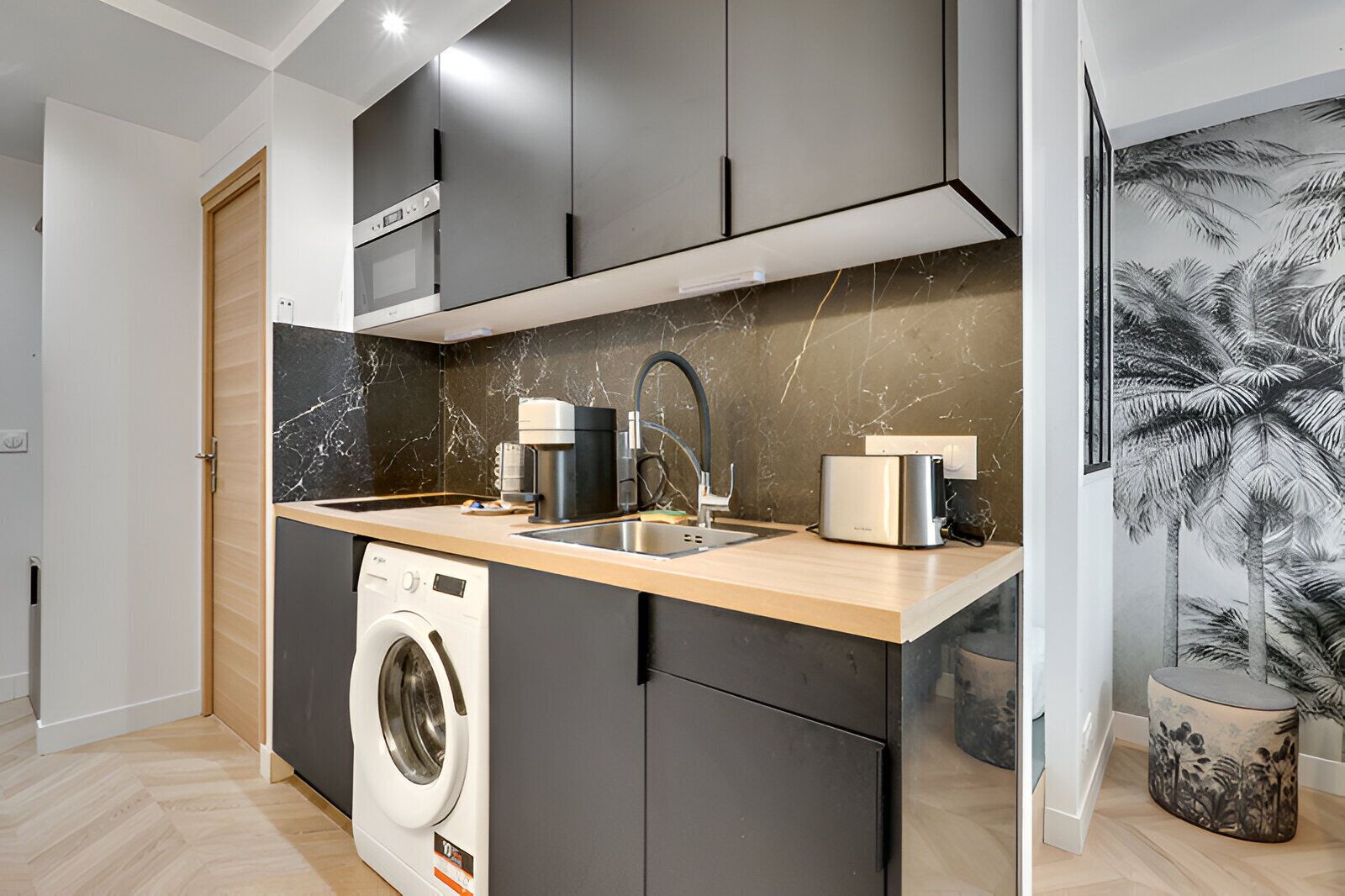 A compact kitchen with a built-in washing machine, a coffee maker, and a toaster.
