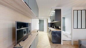 Eine moderne Wohnung mit Fernseher, Küchenzeile und einem Bett.