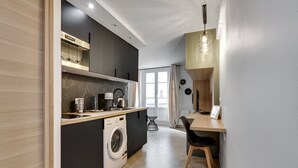 Eine moderne Küche mit integriertem Waschmaschine, einer Essecke mit Tisch und Stühlen sowie einer Pendelleuchte.