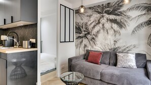 Ein modernes Wohnzimmer mit Küchenbereich, einer Couch mit Kissen und einem großen Wandgemälde.