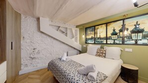 A bedroom with a bed, a white wall with a geometric design, a window with a view of Paris landmarks, and a wooden floor. - TBS 51 - Spacious and modern duplex apartment (Paris)