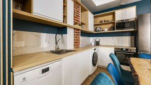 A compact kitchen with a washing machine, a coffee maker, and a built-in oven. - TBS 51 - Spacious and modern duplex apartment (Paris)