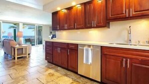 A modern kitchen with wooden cabinets, a stainless steel dishwasher, and a large countertop.