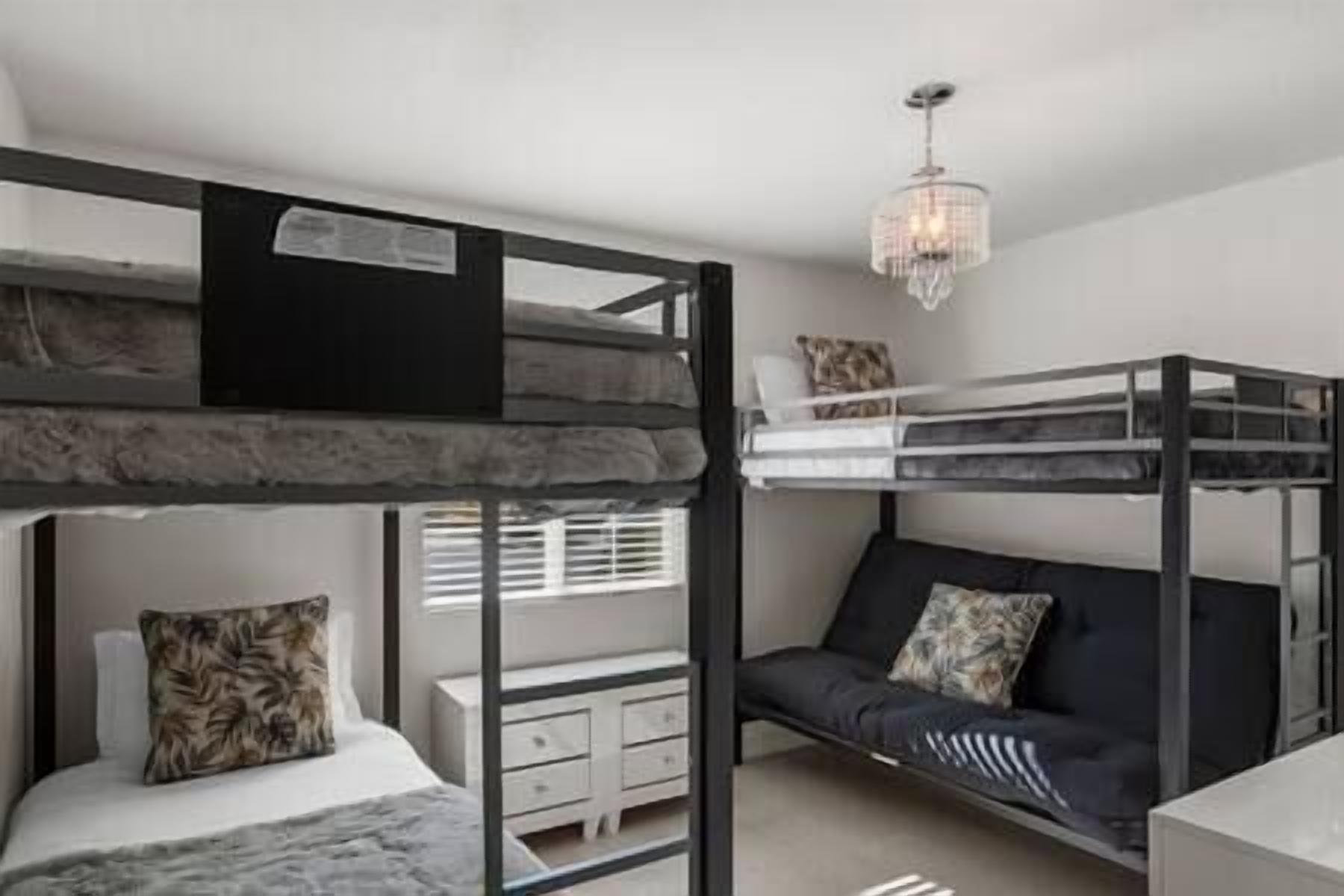 A bunk bed room with a desk and a chandelier.