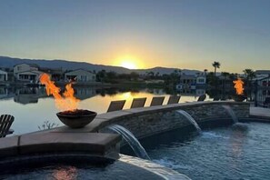 A swimming pool with a waterfall feature and a sunset in the background. - Lakeside Oasis: Game Room, Pool & Spa T2 (Indio)