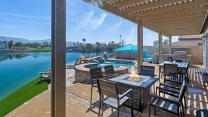 Une terrasse extérieure avec une piscine, des tables, des chaises et un foyer.