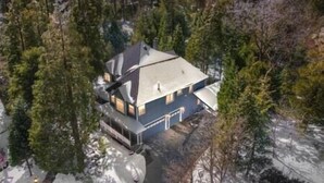 Ein zweistöckiges Haus, umgeben von dichtem Wald.