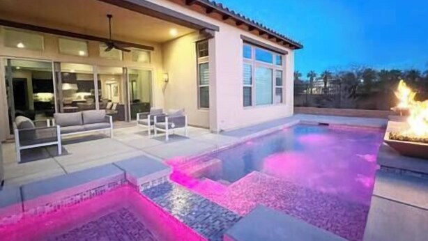 A modern house with a swimming pool, outdoor seating, and a fire feature. - Luxe Desert Oasis: Pool, Spa, Gym & Golf Cart Access Champ (La Quinta)