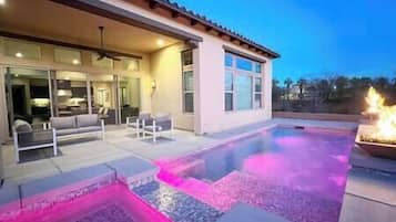 A modern house with a swimming pool, outdoor seating, and a fire feature.