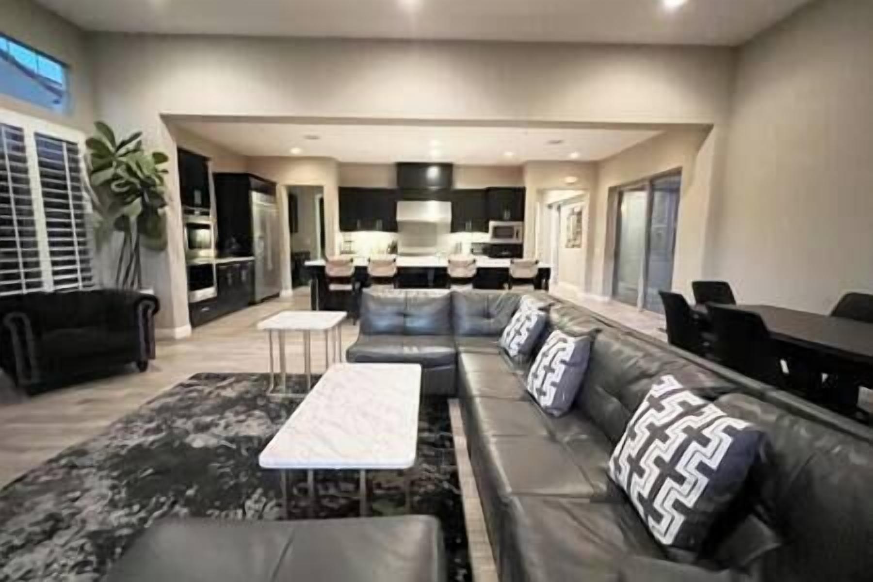 A modern living room with a sectional sofa, a small coffee table, and a dining area with a table and chairs.