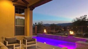 An outdoor patio area with a pool, seating, and a view of the mountains. - Luxe Desert Oasis: Pool, Spa, Gym & Golf Cart Access Champ (La Quinta)