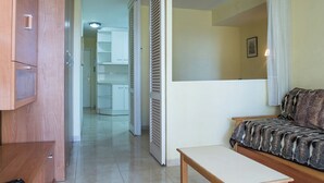 A room with a wooden cabinet, a bench, a white door, and a view into a hallway with a white cabinet and a ceiling light.