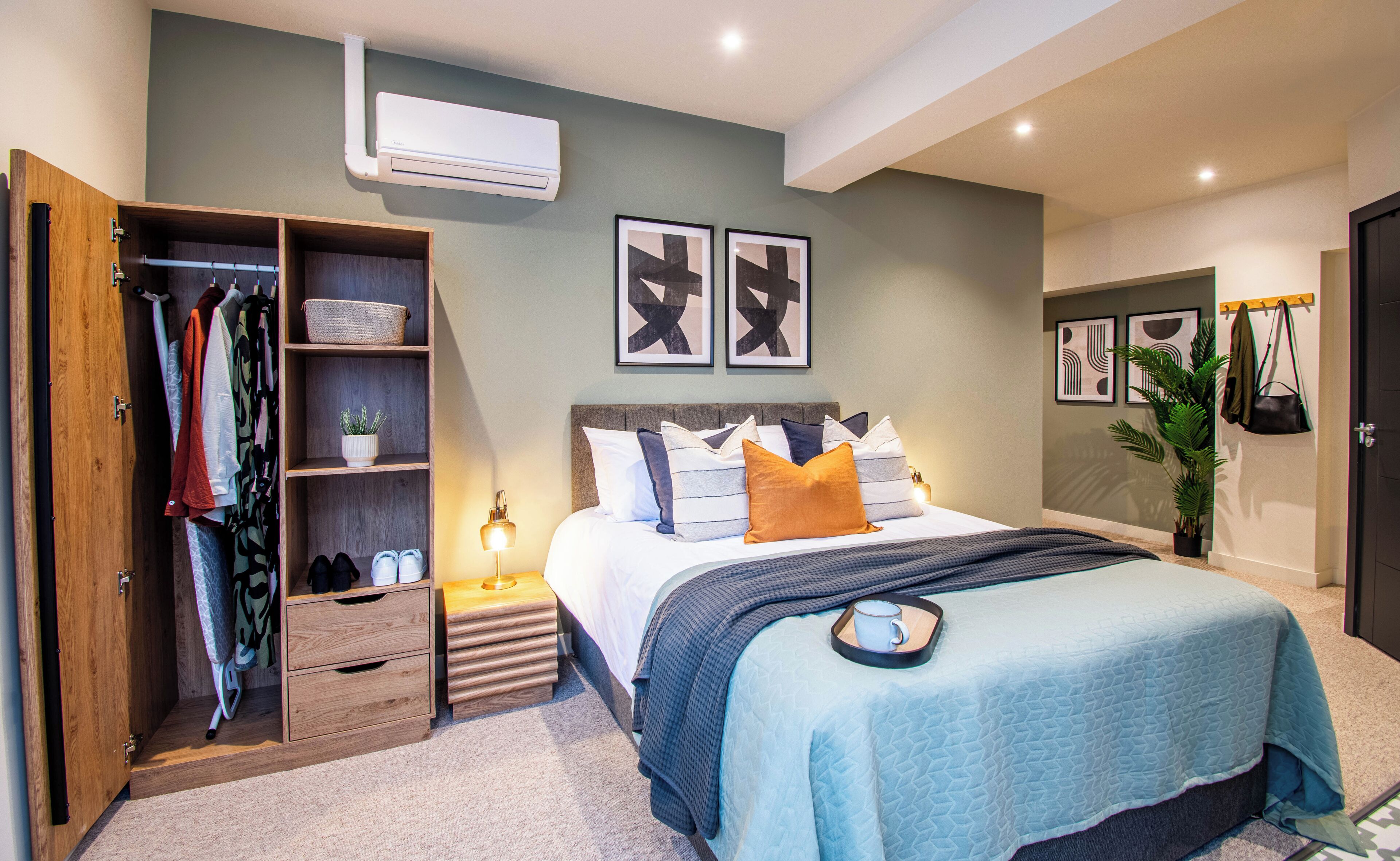 A bedroom with a bed, a wardrobe, a bedside table, and a wall-mounted air conditioner.