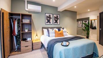 A bedroom with a bed, a wardrobe, a bedside table, and a wall-mounted air conditioner.