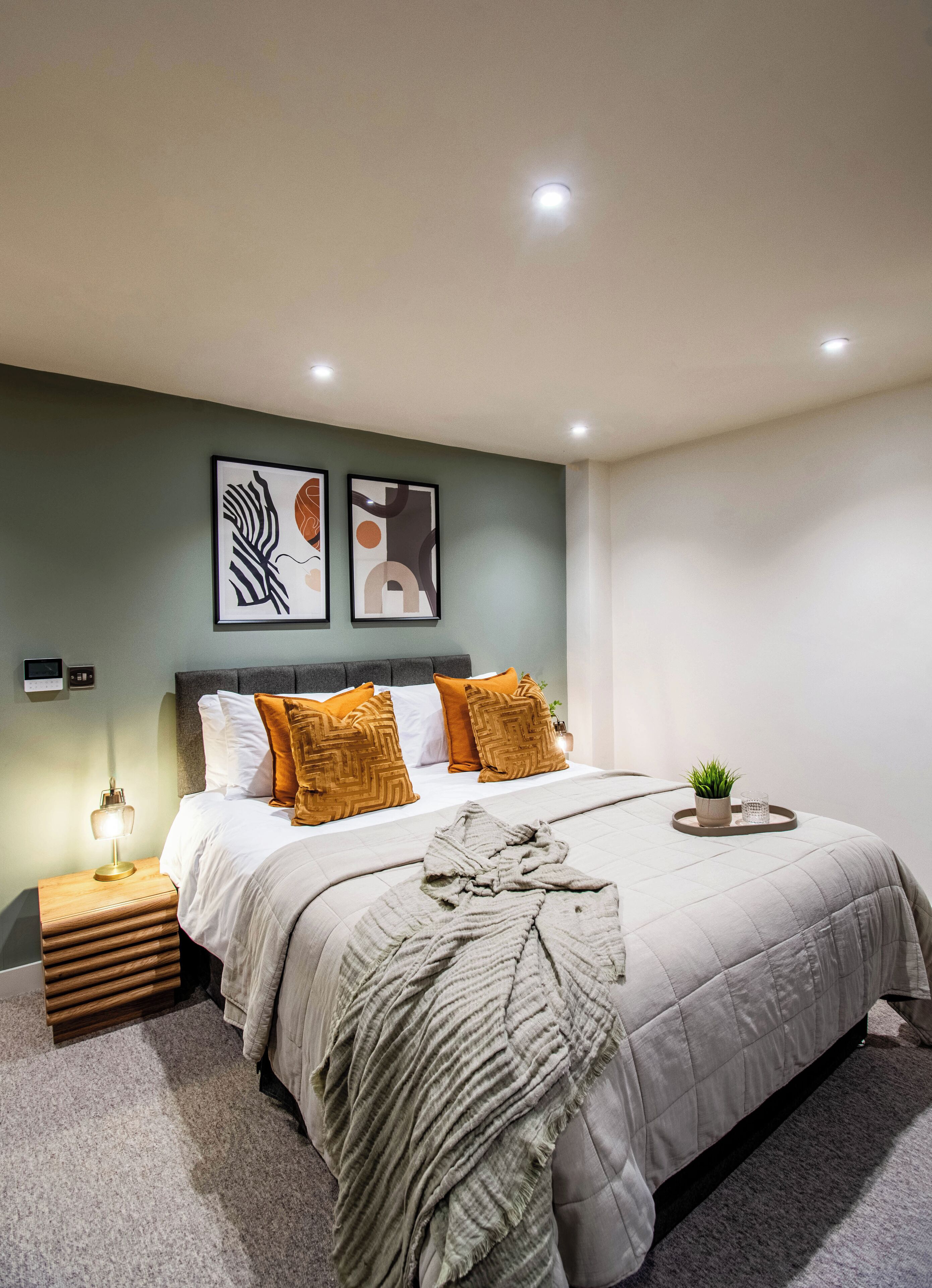 Une chambre à coucher moderne, avec un lit, des tables de chevet et des œuvres d’art murales.