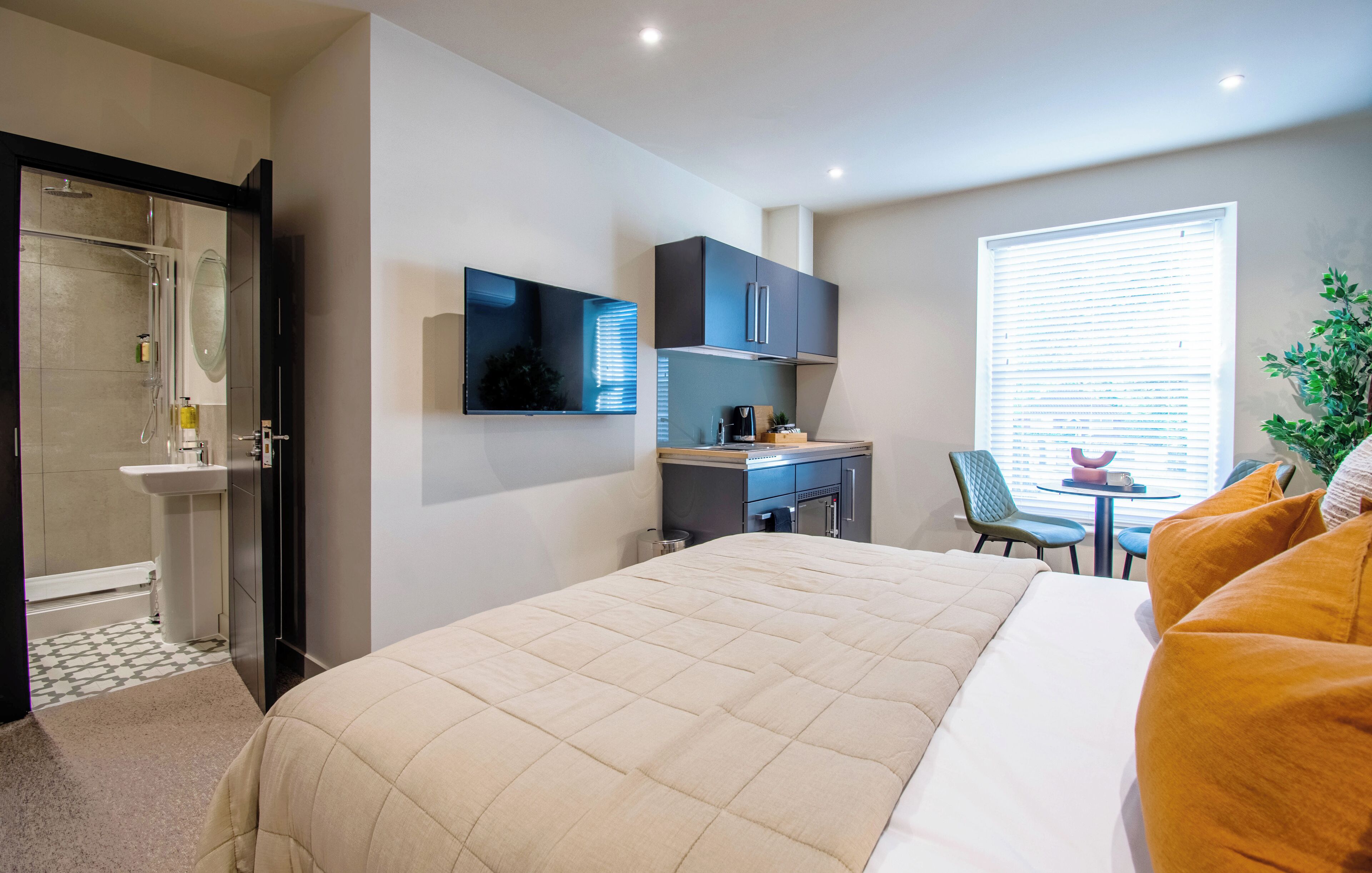 Une chambre d’hôtel avec un lit, un bureau, une douche et une fenêtre avec des stores.