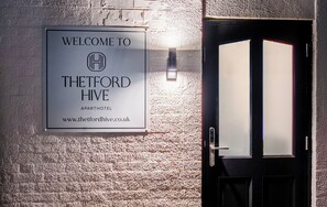 A welcome sign for Thetford Hive, an apartment hotel, with a website URL and a door with frosted glass panels. - Thetford Hive (Thetford)