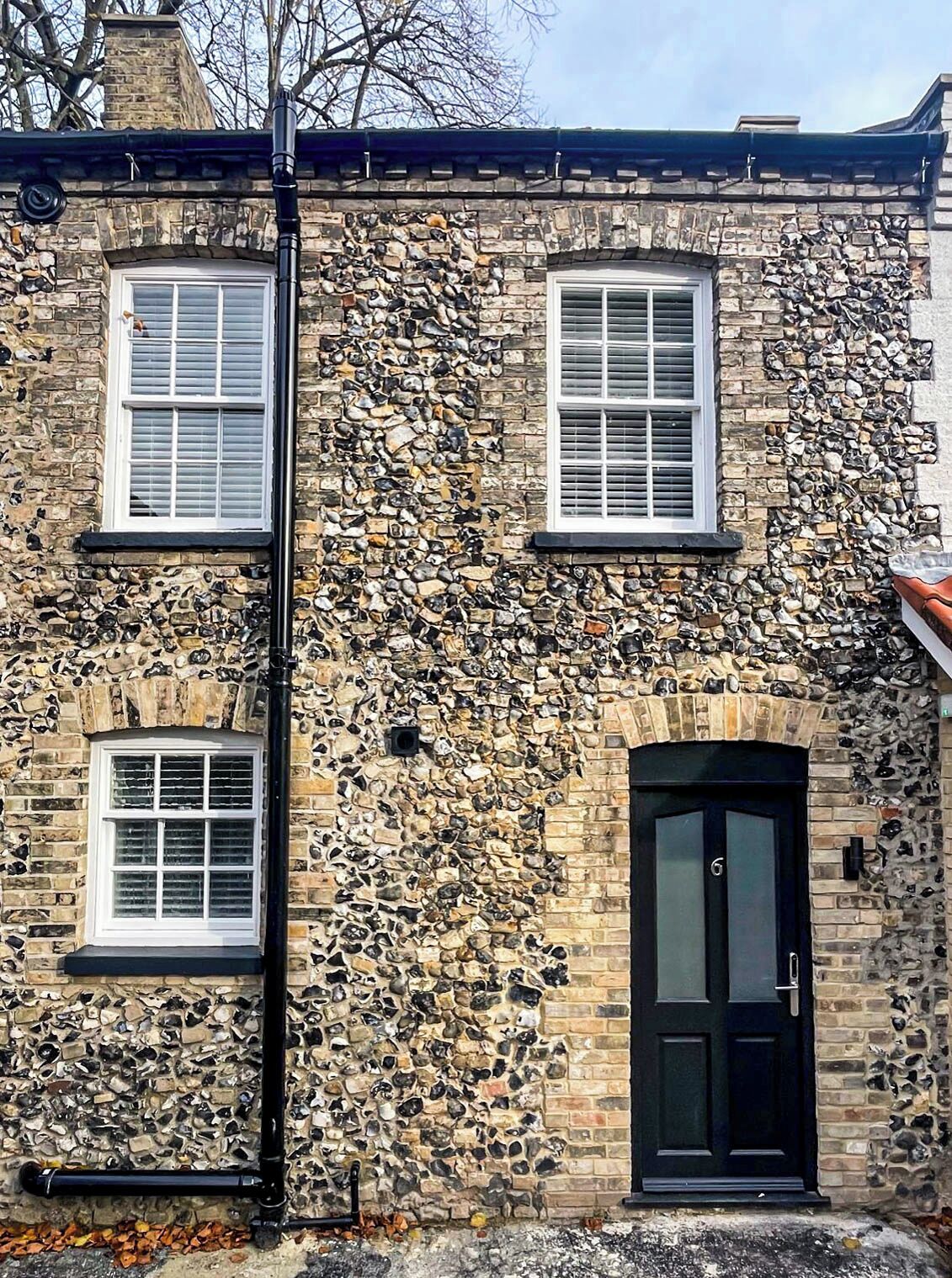 A stone building with two windows and a black door.