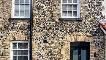 A stone building with two windows and a black door.