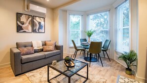 A modern living room with a grey sofa, a glass coffee table, and a dining area with a table and chairs. - Thetford Hive (Thetford)