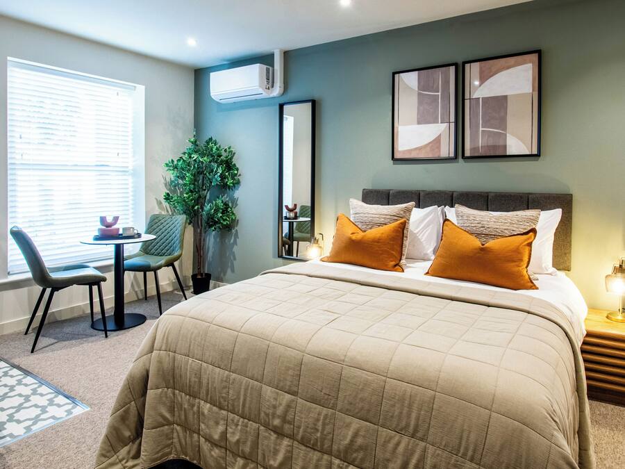 A bedroom with a large bed, a desk, and a chair.