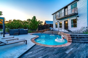 Uma casa moderna com piscina, área de estar externa e escadaria para uma varanda.