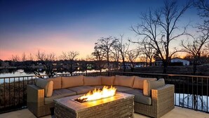 A fire pit with a sofa and cushions on a patio overlooking a body of water. - Lakefront Home w/ Pool, Spa, & Game Room! (Kingsland)