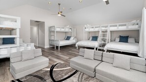 Una habitación moderna y luminosa con literas, un sofá y un ventilador de techo.