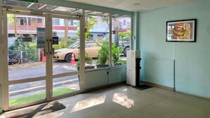 Entrada de un hotel con puerta de cristal, un letrero que dice "KELUAR" y un cuadro en la pared.