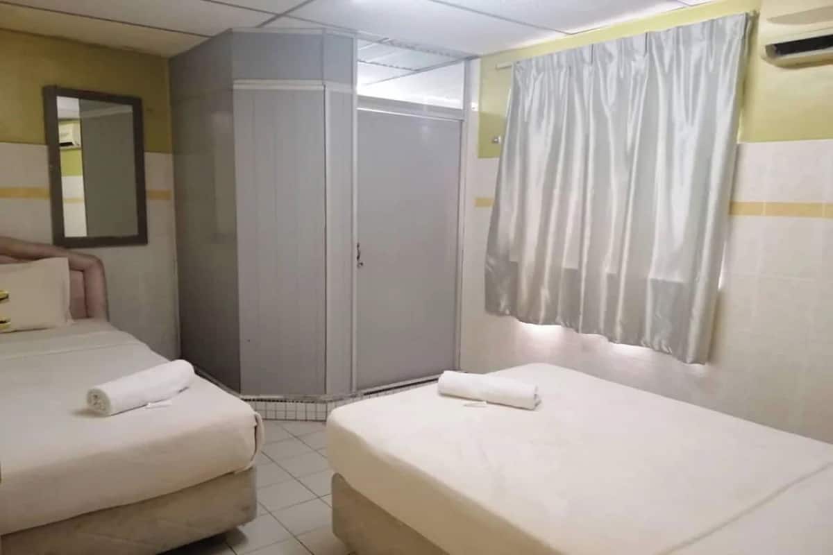 A hotel room with two beds, a wardrobe, a mirror, and a curtain.