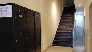 Una escalera conduce a un rellano con una fila de taquillas negras a la izquierda.