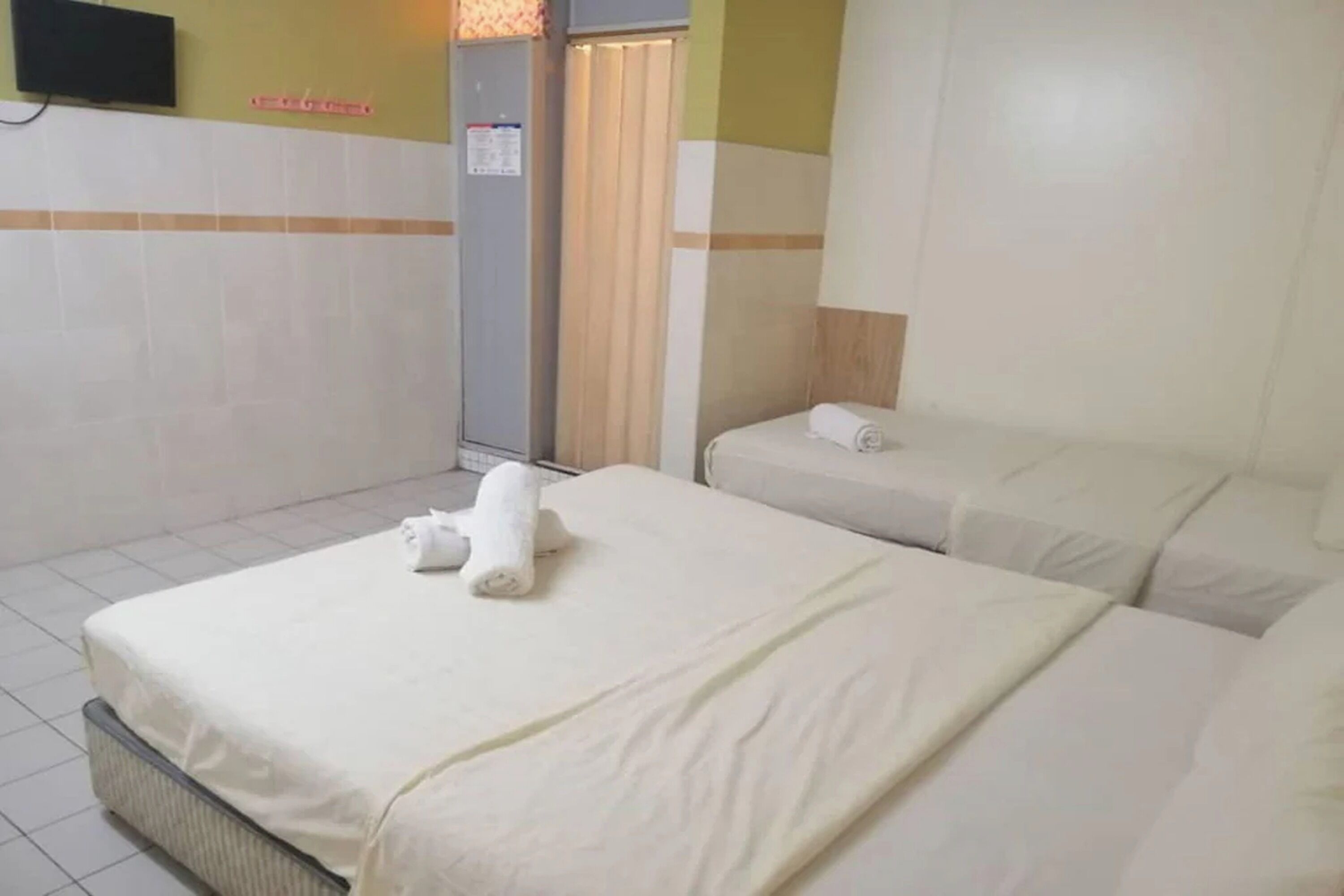 A hotel room with a bed, a bedside table, a wall-mounted TV, and a shower area.