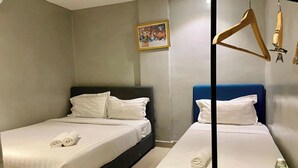 Habitación de hotel con dos camas, cada una con ropa de cama y almohadas blancas. Hay un cuadro en la pared sobre la cama de la izquierda.