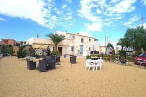 Un edificio con un patio amoblado con muebles de mimbre y una mesa blanca.