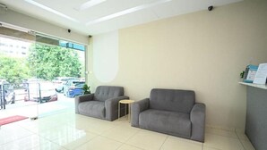 A reception area with two grey sofas, a small round table, and a glass door leading outside. - Swing & Pillows @ Subang SS15 (Subang Jaya)