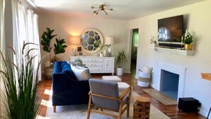 A living room with a blue sofa, wooden chair, and a fireplace. - Caitlin's Cottage - Peaceful 2BR Retreat in North Marion (Marion)
