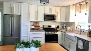 A modern kitchen with white cabinets, stainless steel appliances, and a wooden countertop. - Caitlin's Cottage - Peaceful 2BR Retreat in North Marion (Marion)