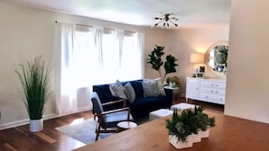 A living room with a blue sofa, a wooden coffee table, and a white cabinet. - Caitlin's Cottage - Peaceful 2BR Retreat in North Marion (Marion)