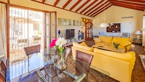 A spacious living room with a yellow sofa, a glass dining table, and a TV. - Cubo's Casa La Paloma / family / free Wi-Fi / private heated pool (Marbella)
