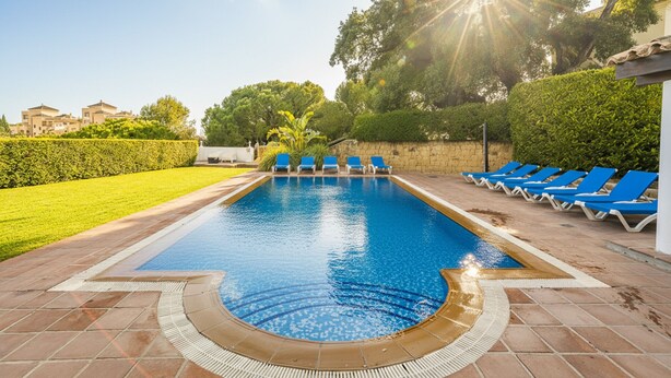 A rectangular swimming pool with blue water, surrounded by a tiled deck. There are blue lounge chairs along the pool's edge. - Cubo's Casa La Paloma / family / free Wi-Fi / private heated pool (Marbella)