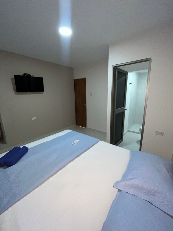 A room with a bed, a TV mounted on the wall, and a door leading to a bathroom. - Hotel stay Golden (Cartagena)