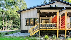 Ein modernes Haus mit überdachter Veranda, einer Treppe und einem gepflegten Garten.