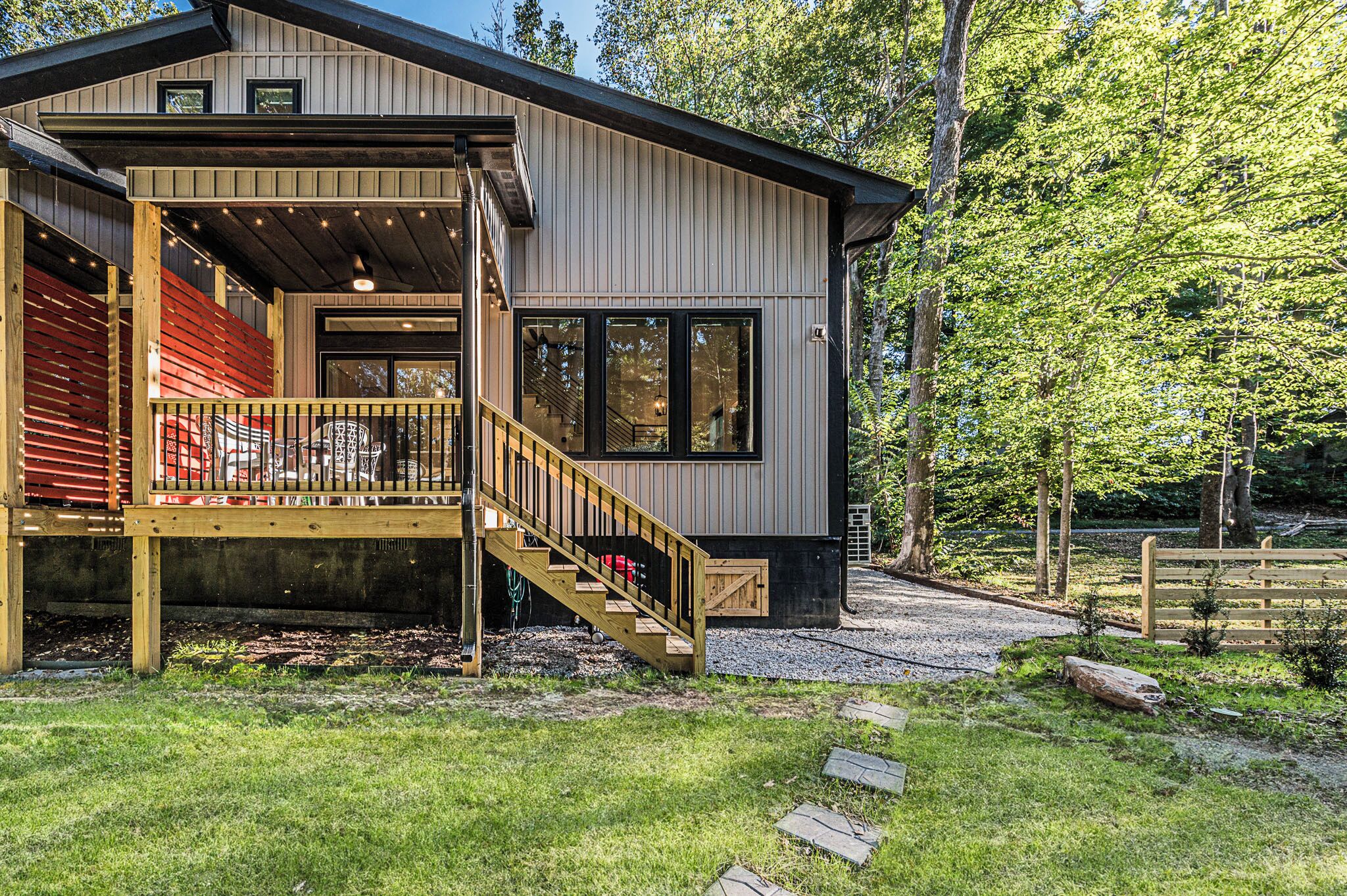A modern house with a wooden deck, a staircase, and a large window.