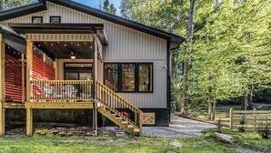 A modern house with a wooden deck, a staircase, and a large window. - Woodside Retreat-A: Modern Home (Scottsville)
