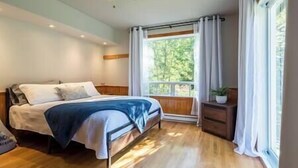 A bedroom with a bed, a nightstand, a window with curtains, and a ceiling fan.