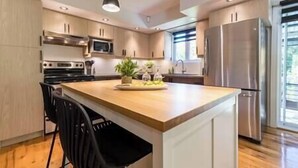 A modern kitchen with a central island, stainless steel appliances, and a view to the outside.
