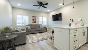 A modern living room with a grey sofa, a small round table, and a ceiling fan. - Pleasant Stay Place - New Build/Zion/Sand Hollow (Hurricane)