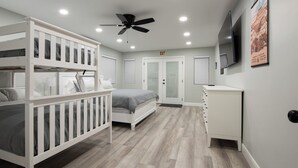 A bedroom with bunk beds, a single bed, a ceiling fan, a TV, and a cabinet. - Pleasant Stay Place - New Build/Zion/Sand Hollow (Hurricane)