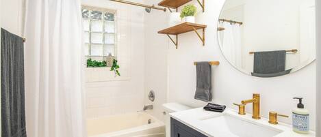 A bathroom with a bathtub, toilet, sink, and a mirror.